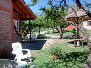 un patio con sillas blancas, una mesa y una sombrilla en Cabañas Quinco en Merlo