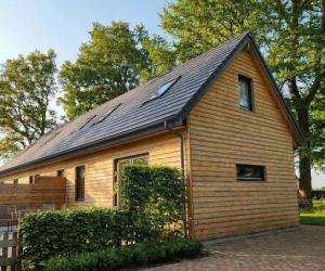 a small wooden house with a black roof at B&B 't Herfter Erf in Zwolle