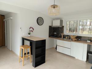 a kitchen with white cabinets and a table and a clock at Appartement Marilou in Pompiey