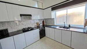 a kitchen with white cabinets and a sink and a window at Haven Stay in Sri Jayewardenepura Kotte