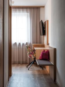 a room with a desk and a chair and a window at Hotel Blitzburg in Brunico