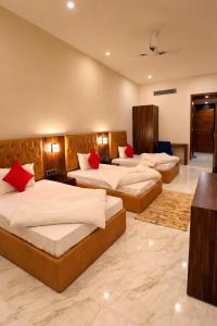 a hotel room with three beds with red pillows at Paradise Resort Paonta in Pāonta Sāhib +5 photos