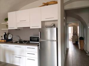 a kitchen with white cabinets and a stainless steel refrigerator at Nene's Home in Sanremo