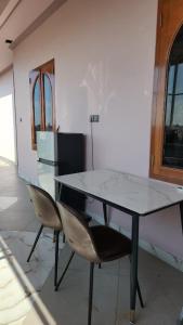 a glass table and two chairs in a room at Velora Inn in Jakarta
