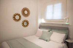 a bedroom with a bed with a window and two mirrors at Infinite Blue Suites in Agia Marina Aegina