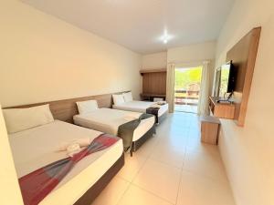 a hotel room with two beds and a tv at Portal do Sol Lençóis Pousada in Barreirinhas