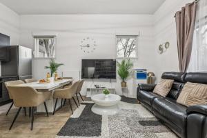 a living room with a black leather couch and a table at NK Apartment in Bobigny in Bobigny