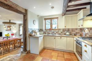 a large kitchen with white cabinets and a table at 3 Bed in Tenterden oc-p36303 in Tenterden