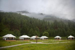 a group of tents in a field in front of a mountain at Haa Valley Camp in Kechungka