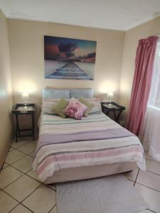 a bedroom with a large bed with pink pillows at Swartbessie Geusthouse in Krugersdorp