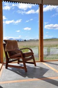 a rocking chair sitting in front of a large window at Hotel Simple Patagonia in Puerto Natales