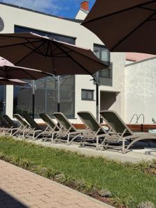 a row of lounge chairs and umbrellas next to a building at 5 Crowns - Osijek - Free EV - Self check in - Pool in Osijek