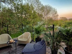 a patio with chairs and plants on a deck at Domy w ogrodzie - Riverfront cabins in Poznań