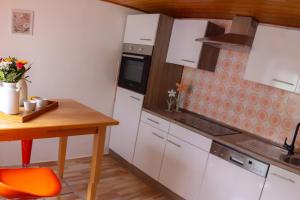 a kitchen with white cabinets and a table and a stove at Elfriedes' Ferienhäuschen in Marktschorgast +10 photos