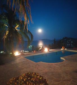 a swimming pool at night with a full moon at Lilian Horizon in Tolo