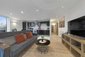 a living room with a gray couch and a kitchen at Alaska apartmans in London +5 photos