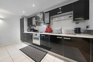 a kitchen with black cabinets and a kitchen rug at Alaska apartmans in London