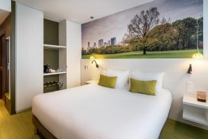 a bedroom with a large white bed with a painting on the wall at BW Plus Central Park Hotel & Spa in La Rochelle