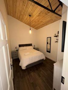 a bedroom with a bed and a wooden ceiling at The Stags Den in Longton