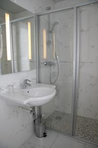 a white bathroom with a sink and a shower at Hotel Bellevue Saint-Lazare in Paris