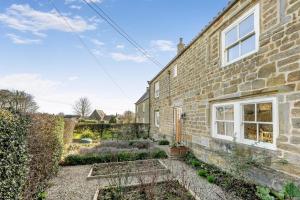 an exterior view of a brick house with a garden at 4 Bed in Borrowby oc-o36892 in Borrowby