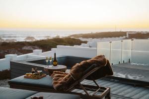 a patio with a chair and a table with wine glasses at Jonesy's Place on the Beach in Yzerfontein +168 photos