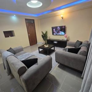 a living room with two couches and a flat screen tv at Sing' Homes in Eldoret