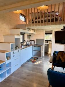 a kitchen with white cabinets and a wooden ceiling at Le Cabanon - Tiny House 150m de la Plage in Portbail