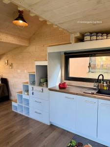 a kitchen with white cabinets and a window at Le Cabanon - Tiny House 150m de la Plage in Portbail