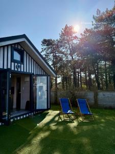 two blue chairs sitting in a yard next to a house at Le Cabanon - Tiny House 150m de la Plage in Portbail
