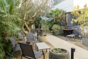 a patio with chairs and tables and trees at BW Plus Central Park Hotel & Spa in La Rochelle