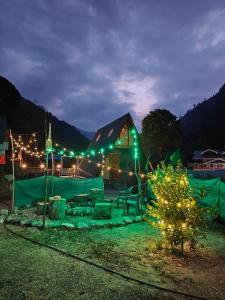 a cabin lit up at night with christmas lights at Nirvana River Nest in Sainj