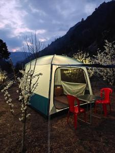 a tent with a table and two chairs in a field at Nirvana River Nest in Sainj