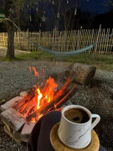 a cup of coffee sitting next to a campfire at Campsite under two oaks in Itʼkhvisi