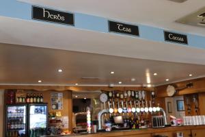 a bar in a restaurant with signs on the wall at Harry's Hotel in Aberystwyth +2 photos