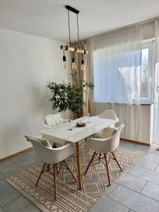 a dining room with a white table and chairs at Gemütliche, sonnendurchflutete Ferienwohnung in Bodenseenähe am Säntisblick in Herdwangen-Schönach