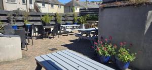 a patio with tables and chairs and a bench and flowers at Harry's Hotel in Aberystwyth