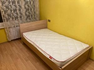 a small bed in a room with a yellow wall at Apiņa 18 in Valmiera