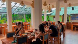 a group of people sitting at tables in a restaurant at Rock View Hostel Ella in Ella