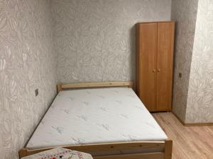 a small bedroom with a bed and a wooden cabinet at Apiņa 18 in Valmiera