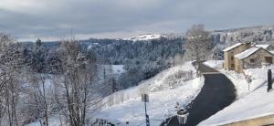 a snow covered hill with a house and a building at Atelier du pont de Mars in Mars