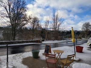 a table and chairs in the snow next to a river at Atelier du pont de Mars in Mars