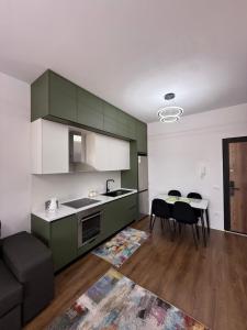 a kitchen with green cabinets and a table and chairs at White Apartment in Kamëz