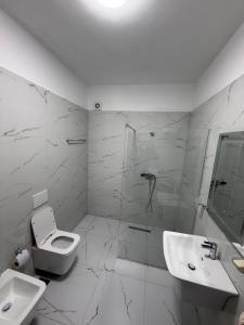 a bathroom with a toilet and a sink and a shower at White Apartment in Kamëz +9 photos