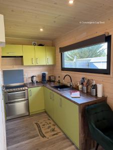 a small kitchen with yellow cabinets and a window at La Roulotte - Tiny House 150m de la Plage in Portbail