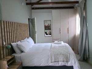 ein Schlafzimmer mit einem großen Bett mit weißer Bettwäsche in der Unterkunft Leipoldt Self-Catering Accommodation in Secunda