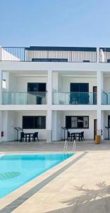 a large white building with a swimming pool at Arbor Boutique Stay in Brufut