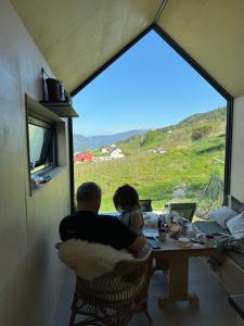 a man and a woman sitting at a table looking out a window at Charming tiny house with panorama view in Sandane