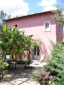 une maison rose avec un jardin devant elle dans l'établissement A zerbi, à Cittanova