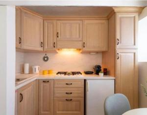 a kitchen with wooden cabinets and a stove top oven at Tiny Apartment on the Lake in Tremezzo